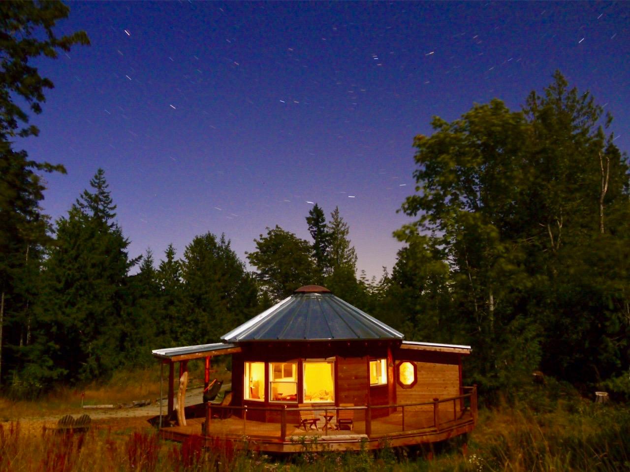 Small wooden yurt lighting up the night sky