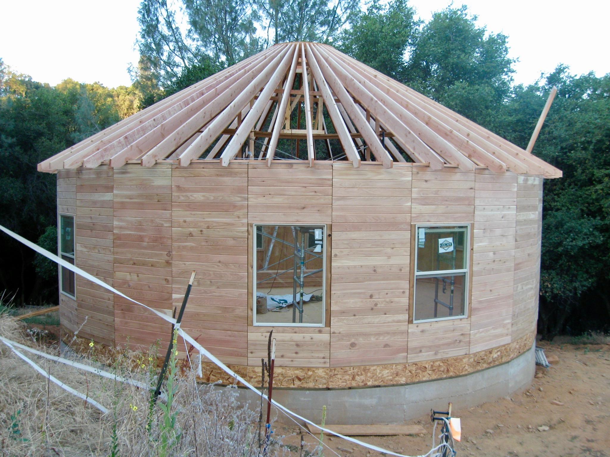 Wooden yurt under construction with rafters installed